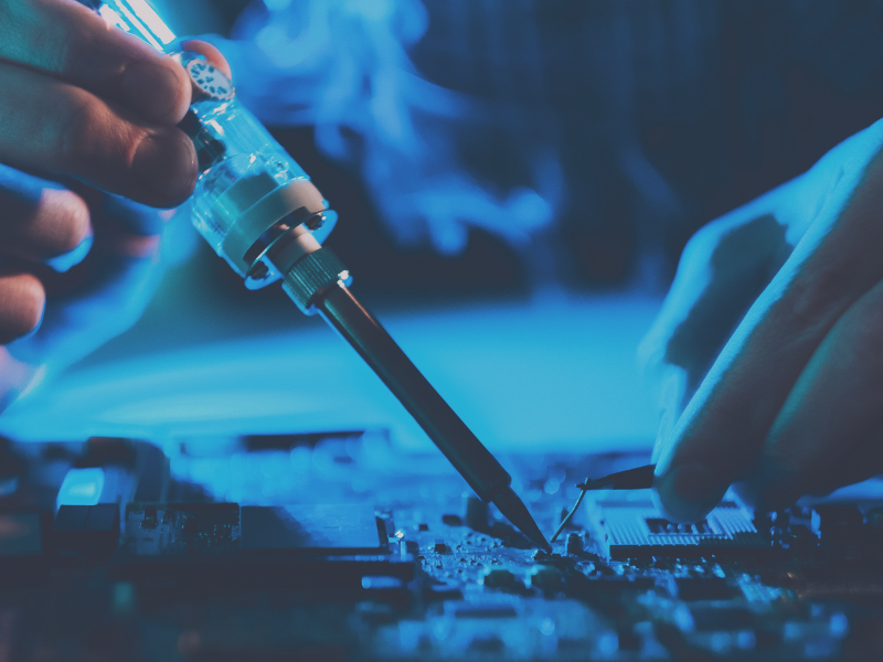 Photo of the hands of a service engineer holding a screwdriver while repairing a part.