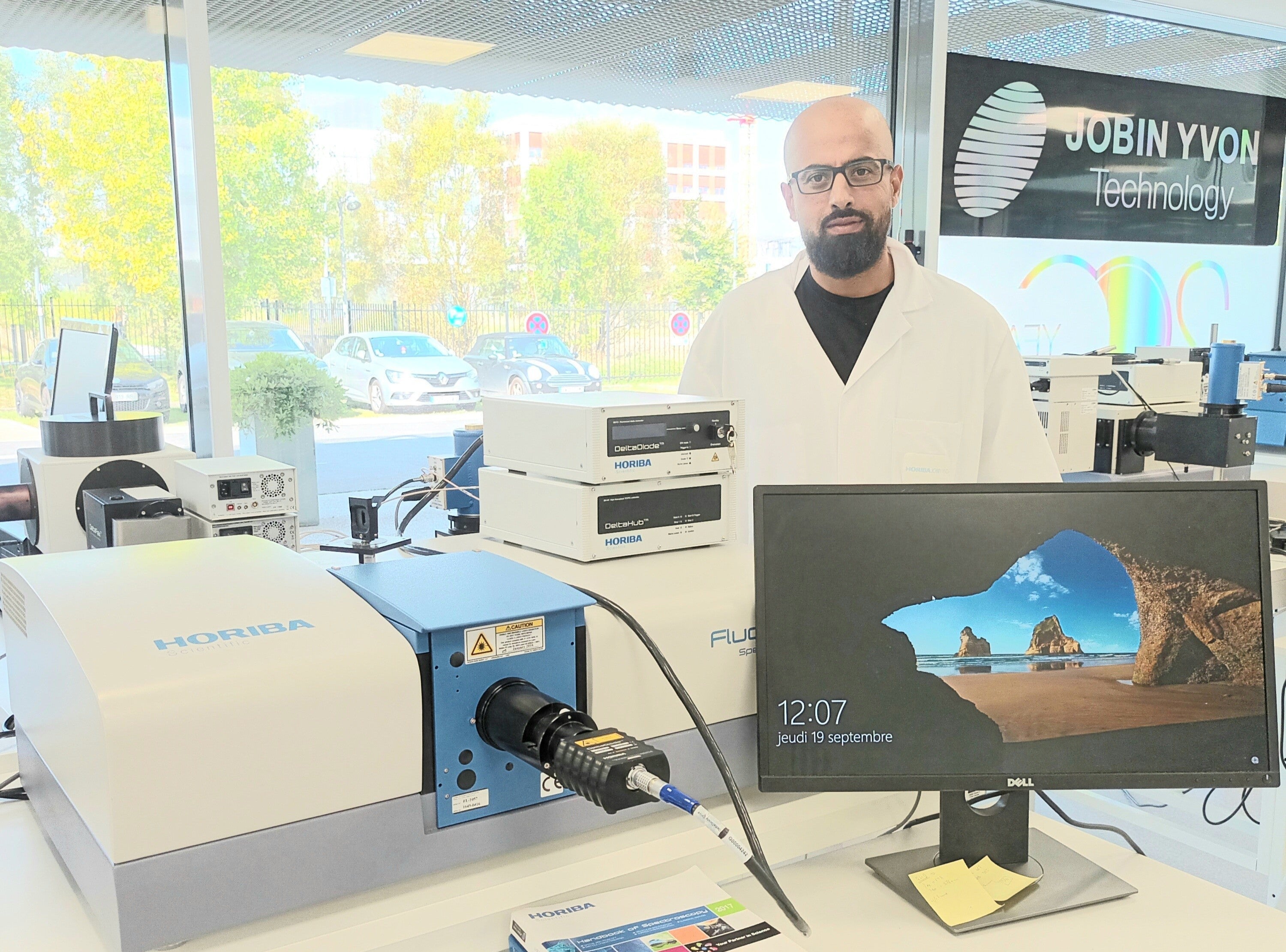 Photo of our Expert Hssen Fares behind his fluorolog instrument in the analytical solution plaza at HORIBA France