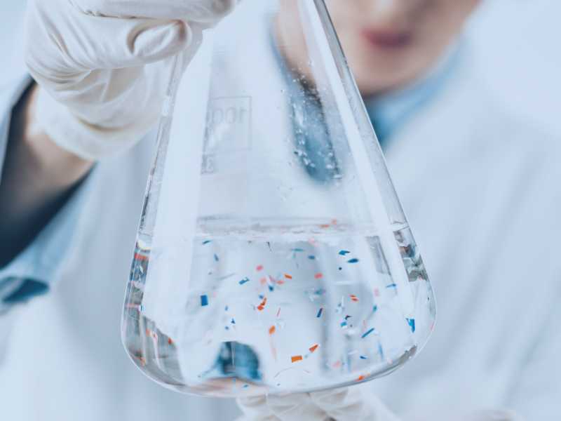 Photo of a beaker containing water and microplastic particles