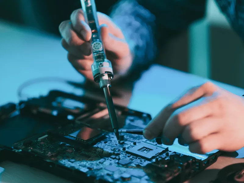 Photo of the hands of a service engineer holding a screwdriver while repairing a part.