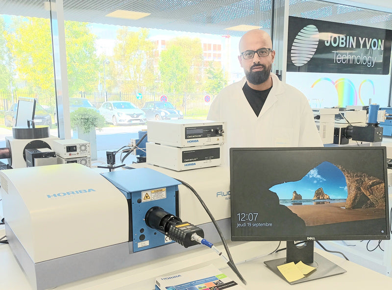 Photo of our Expert Hssen Fares behind his fluorolog instrument in the analytical solution plaza at HORIBA France