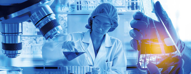 Photo of a chemist analyzing samples with a beaker and microscope